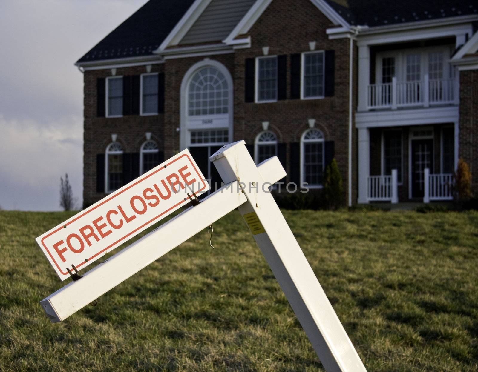 Modern house with crooked foreclosure sign in suburbs