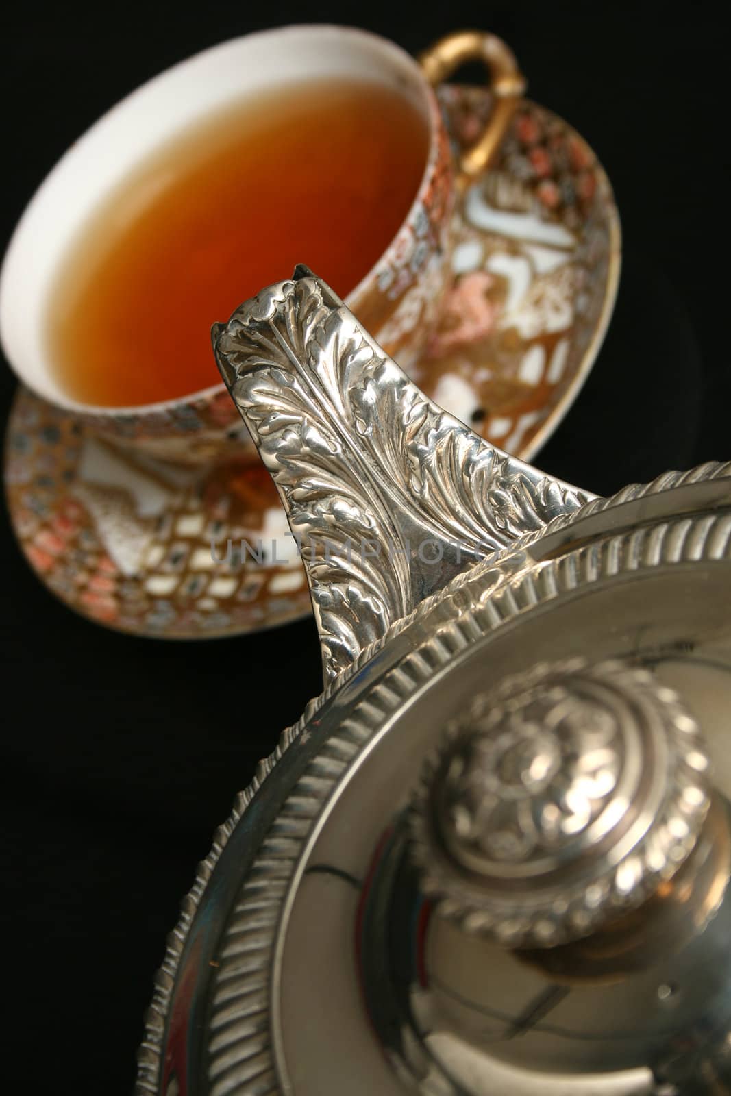 Silver teapot pouring tea into antique chinese cup