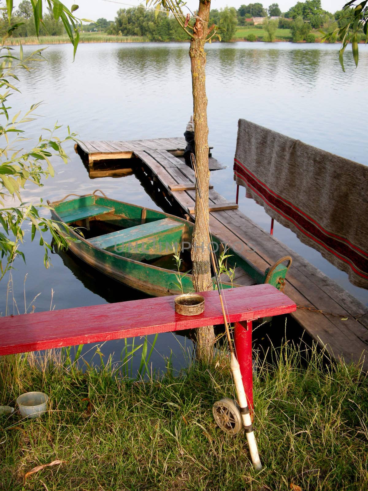 red wooden  bench  with a fishing rod on the shore of Lake
