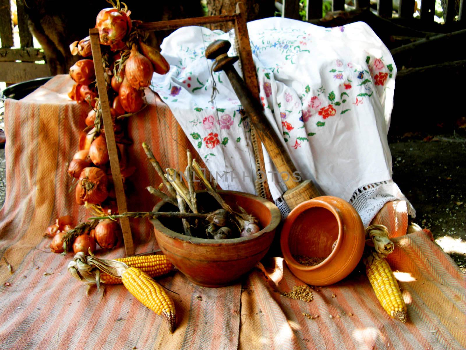 Rural still life of a pot, onions, garlic and  maize