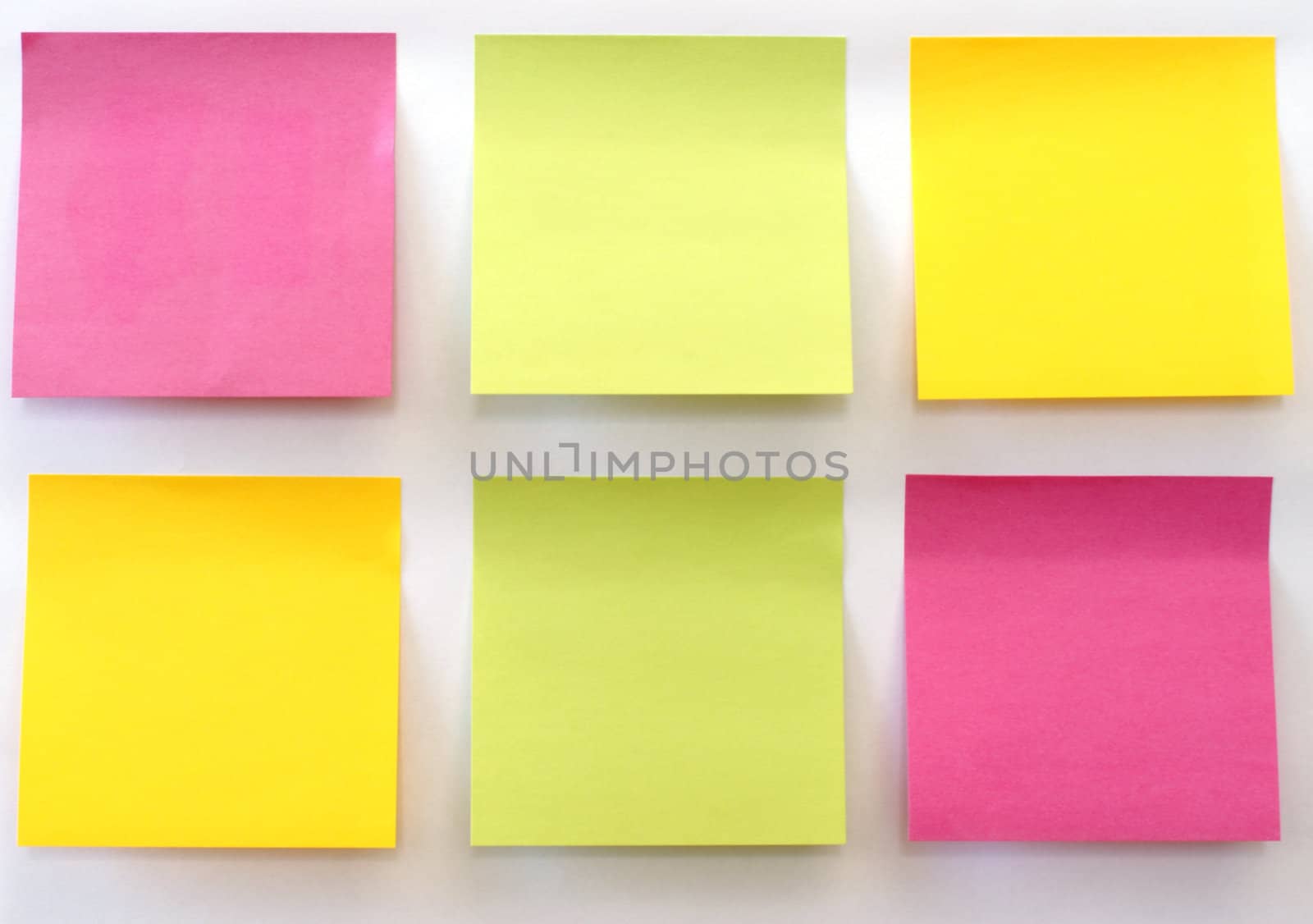 Six multicolored sticky notes stuck on a white wall.