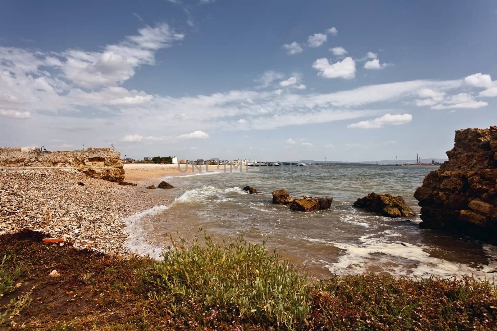 Beach on the banks of the Tejo river with an old boat station in background.