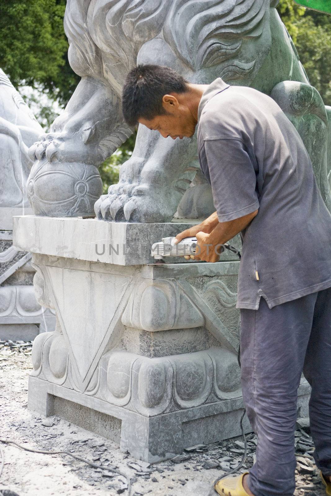 Image of a Chinese craftsman sculpturing a stone lion at Guilin, China.
