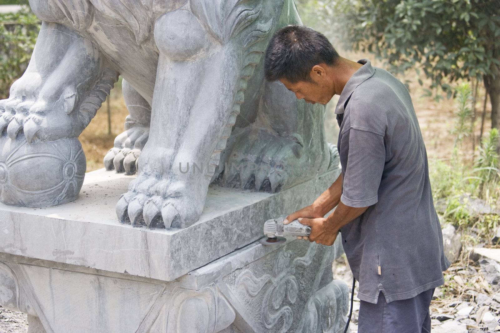 Image of a Chinese craftsman sculpturing a stone lion at Guilin, China.