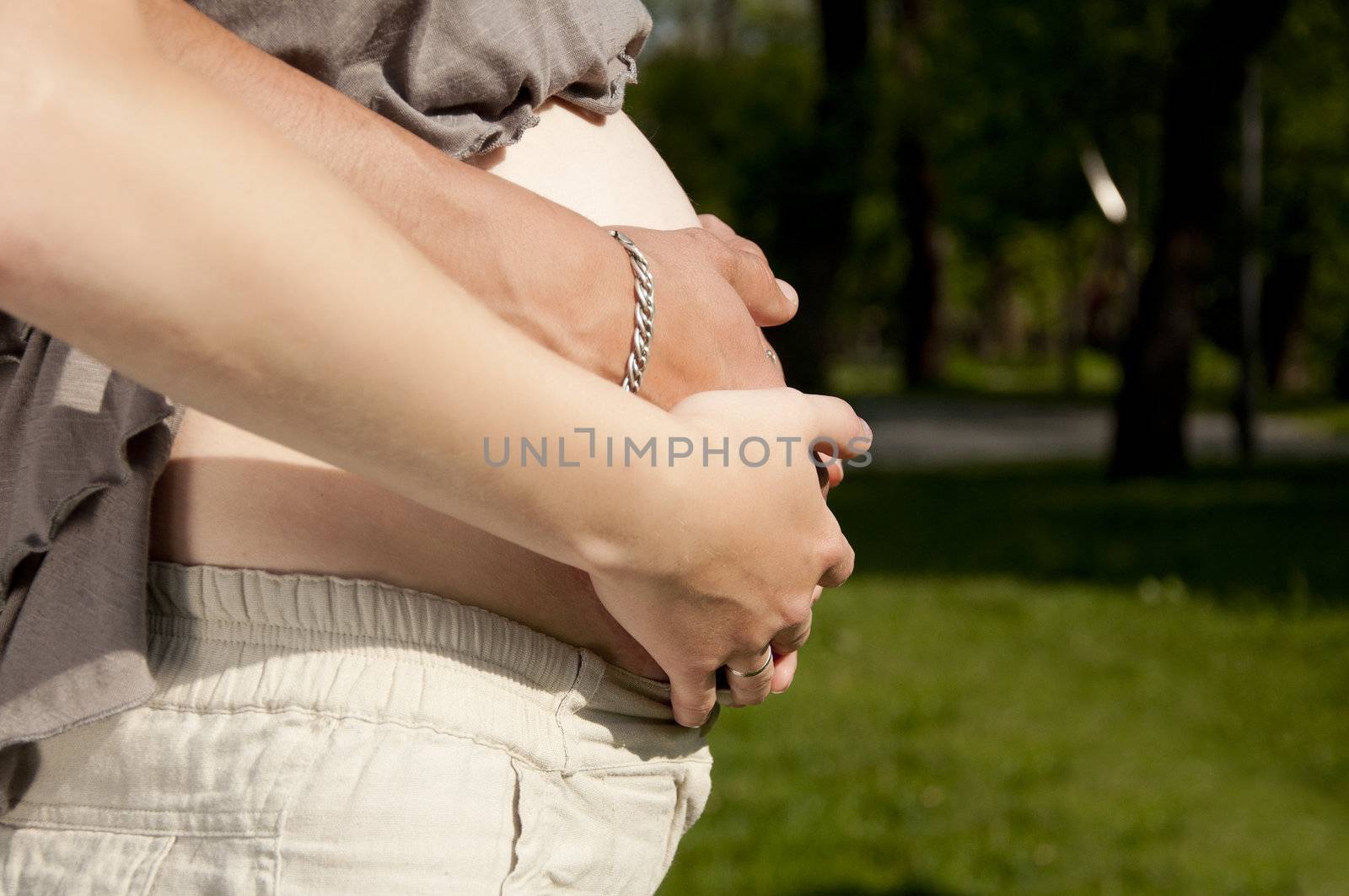 Man's and female hands embrace a pregnant stomach