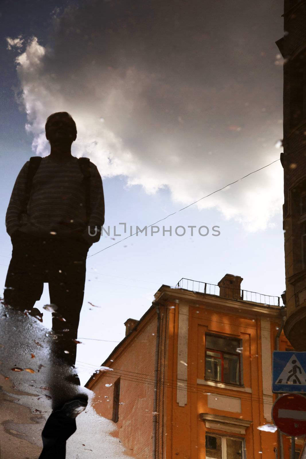 Reflection of a building, clouds and men in water