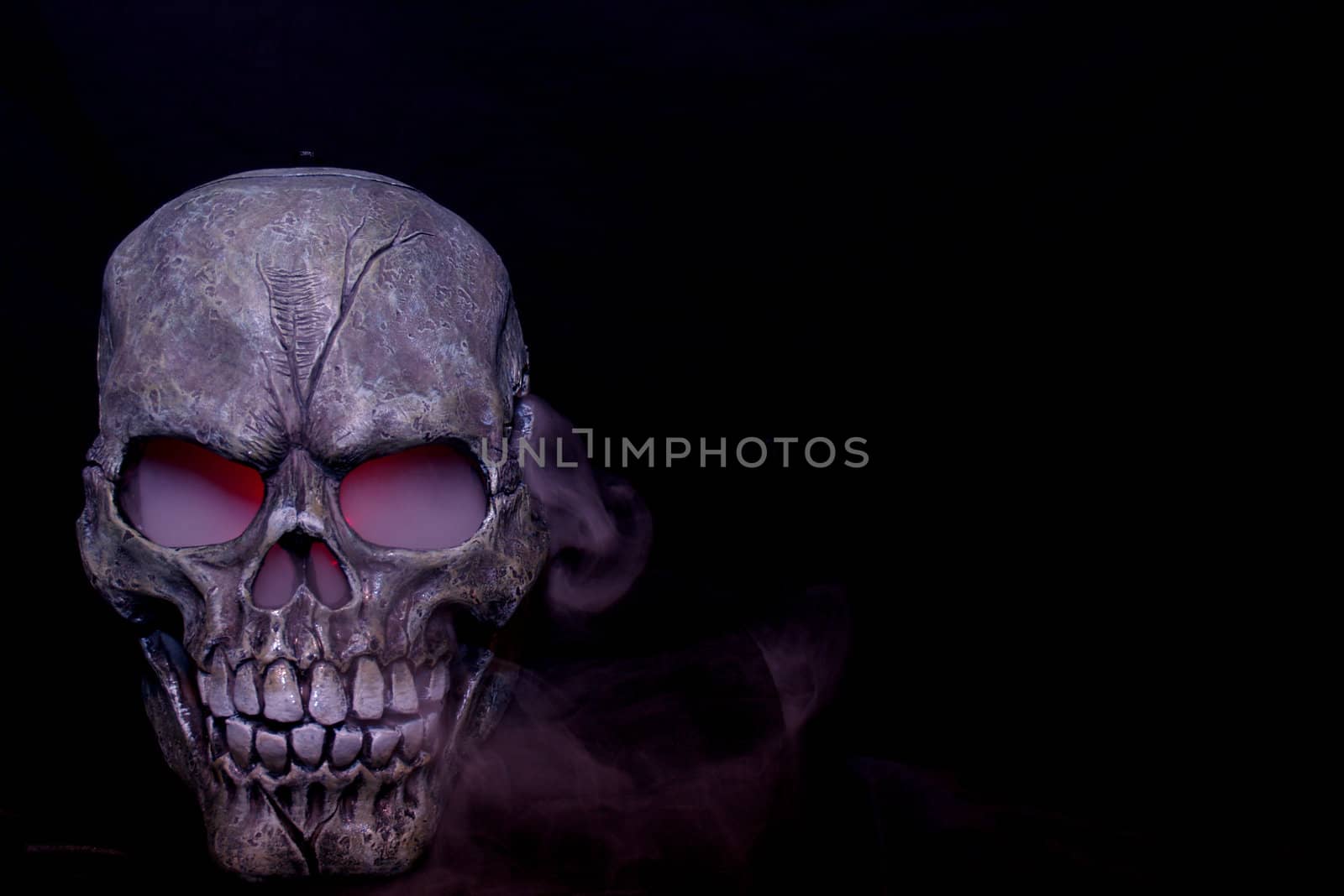 A Halloween prop skull with fog coming from it's eyes and nose.
