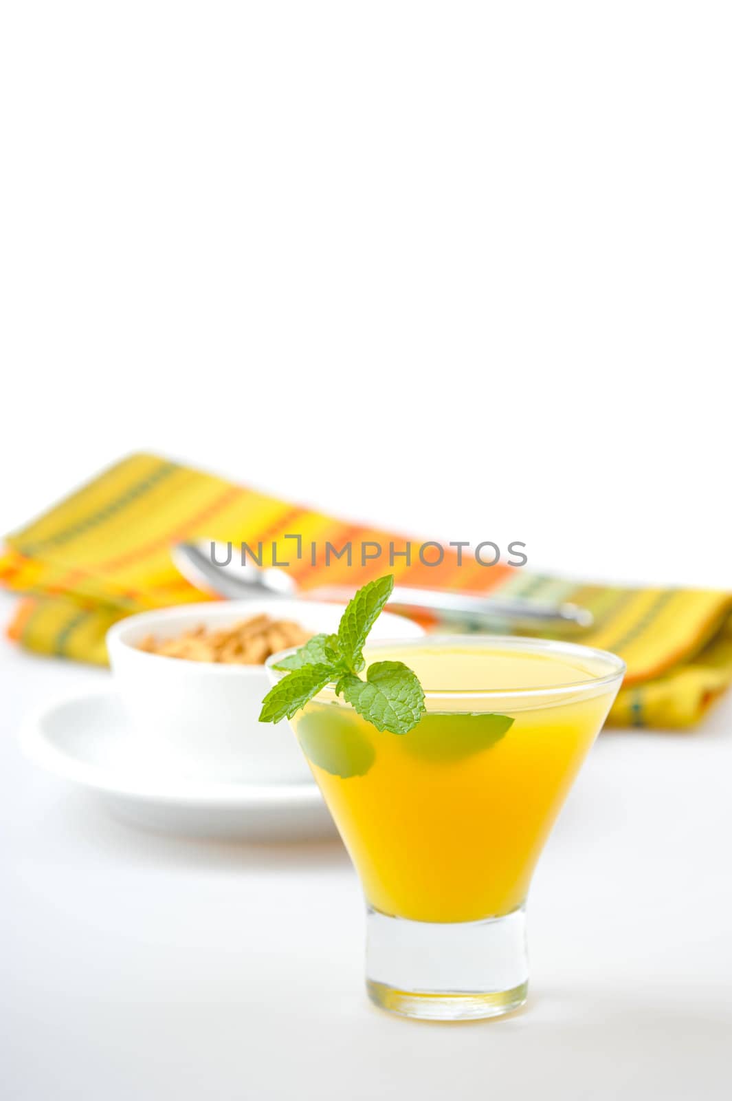 Glass of fresh orange juice garnished with a sprig of mint.