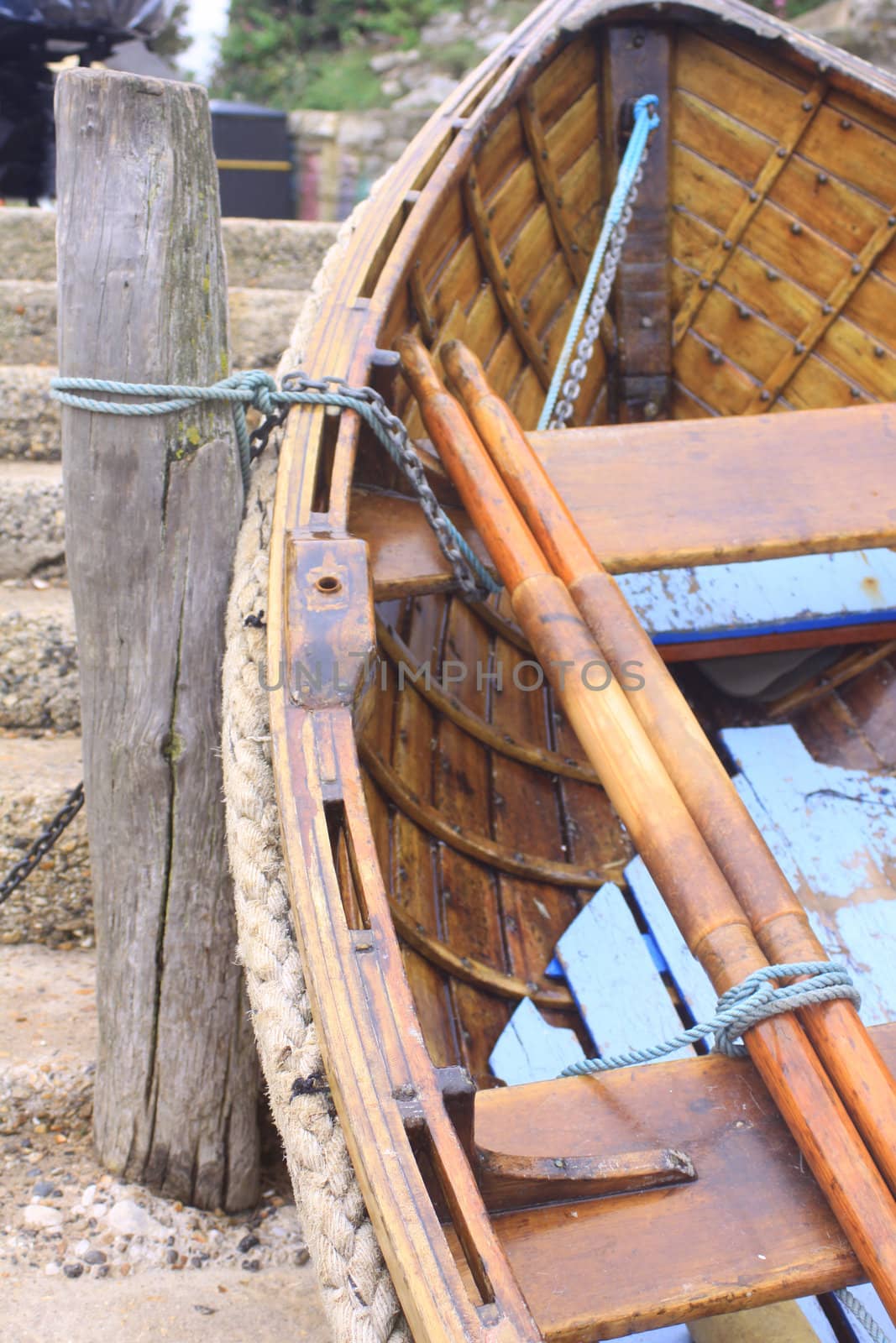 A small wooden rowing boat tied to a wooden jetty post.