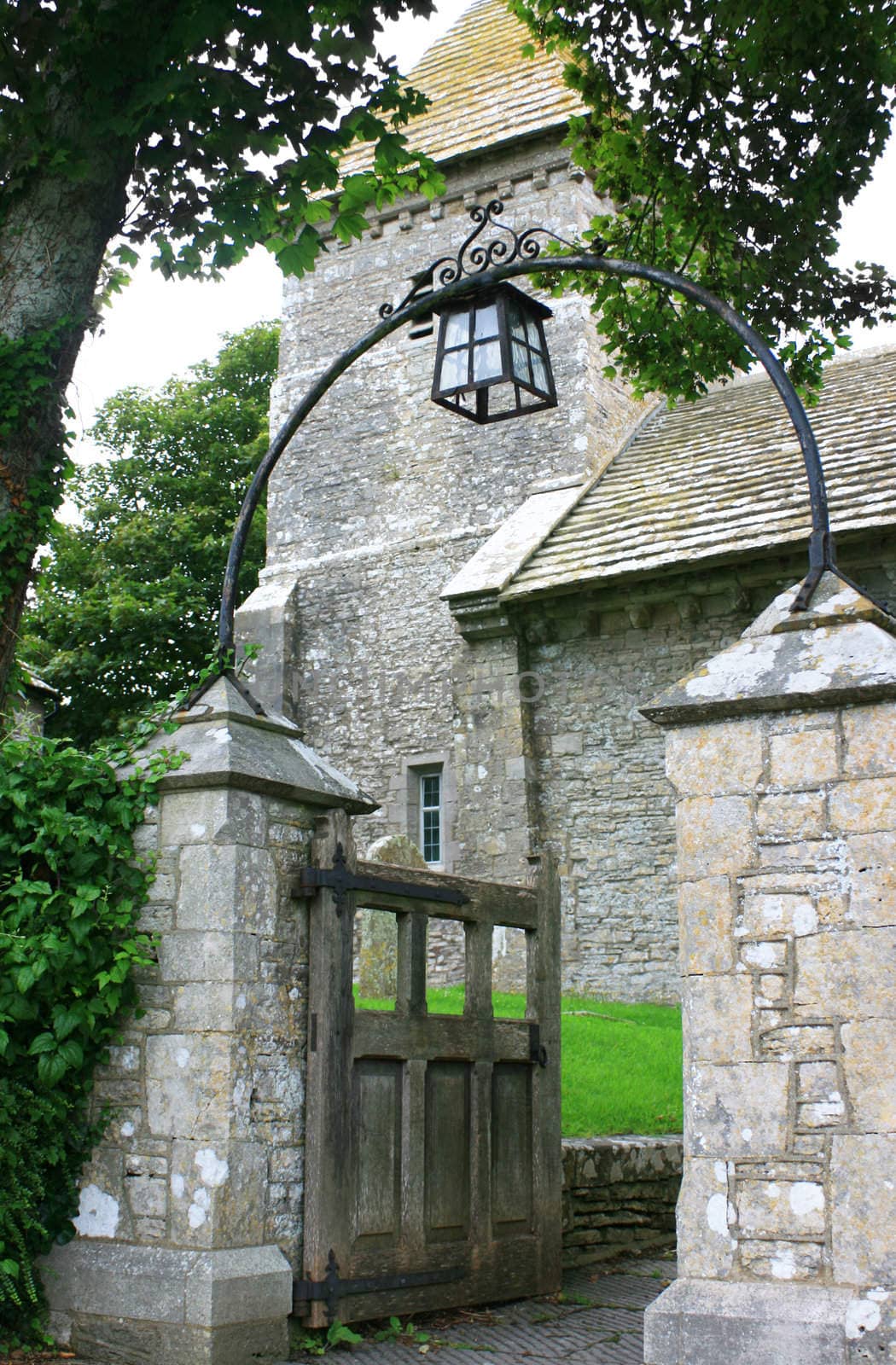 A rural medieval church entrance, gate and stone pillars, found in Dorset, UK.