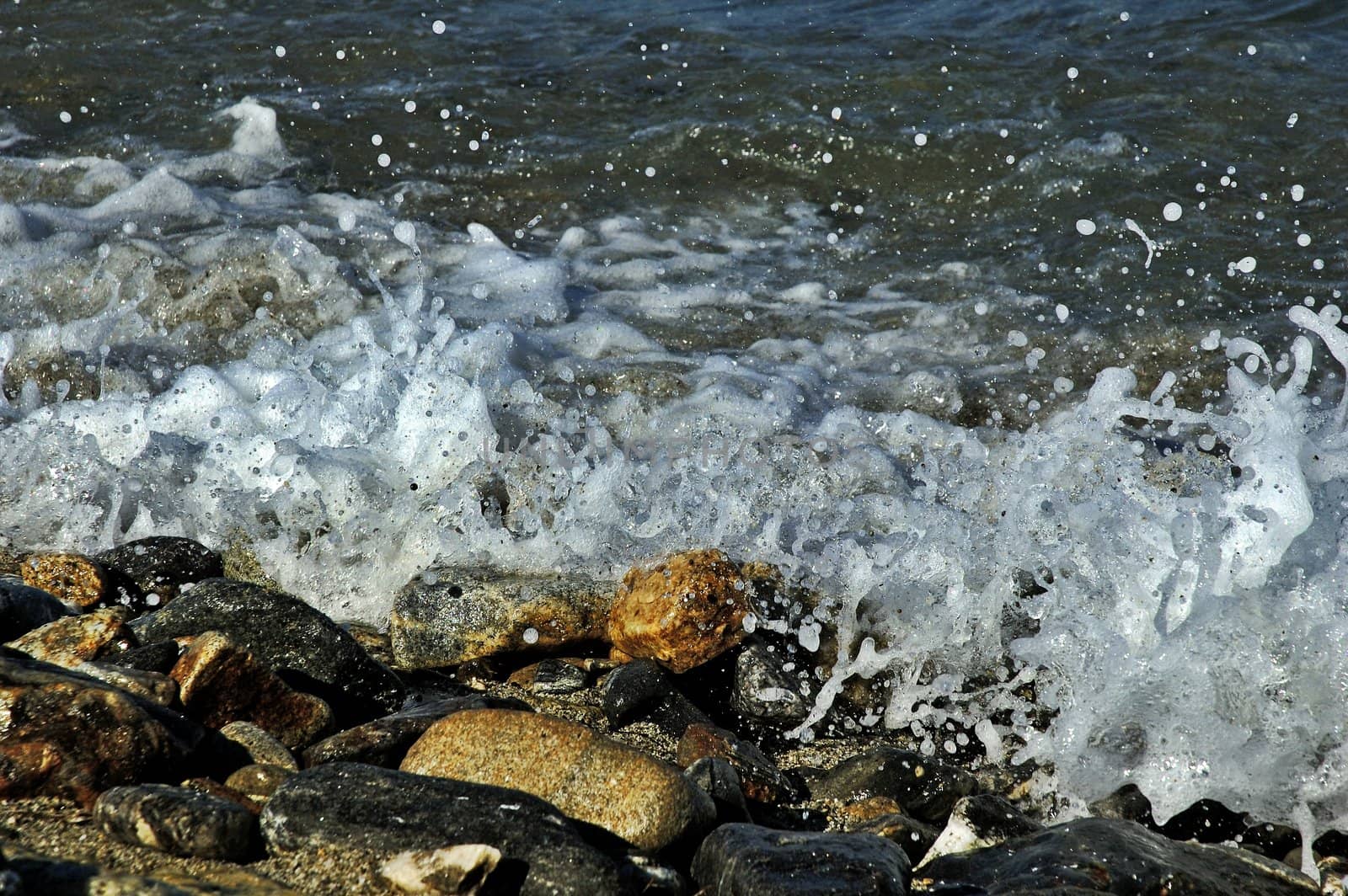 Sea foam splashing against pebbles
