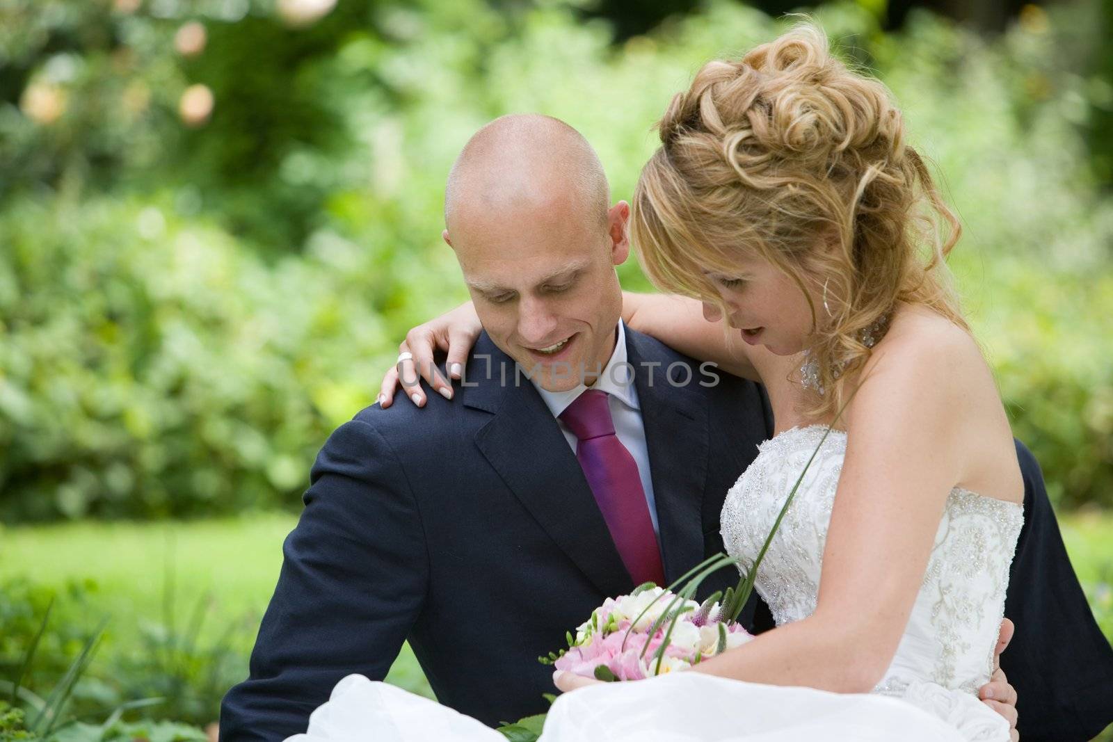 Beautiful bride and groom sitting on a lawn and relaxing for a moment