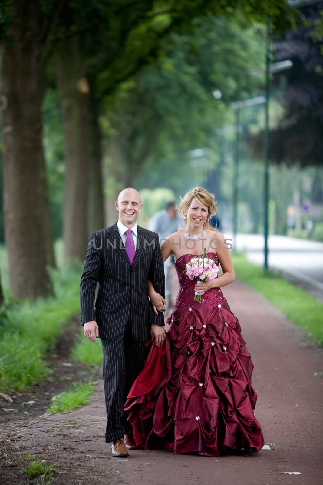 Beautiful bride and groom walking along a bicycle path