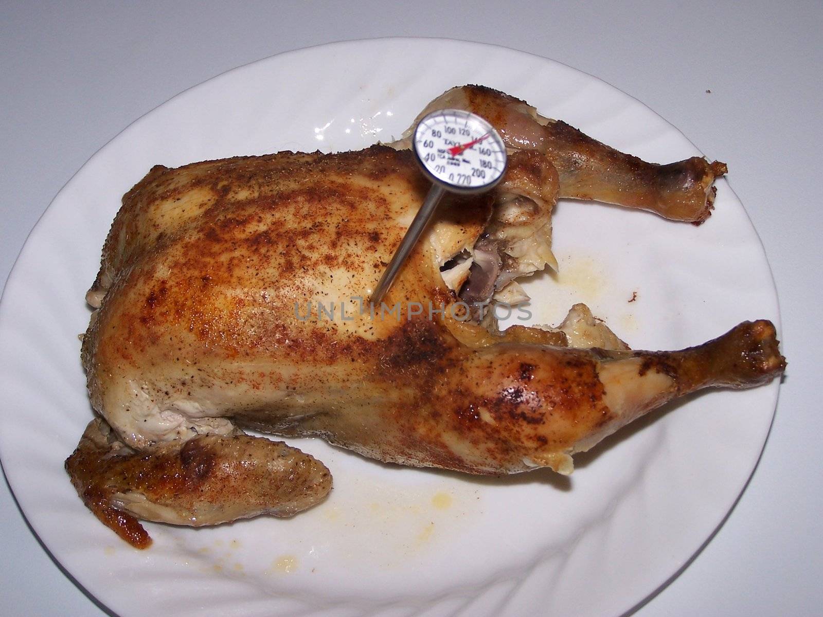 thermometer stuck in roasted chicken to see if its cooked