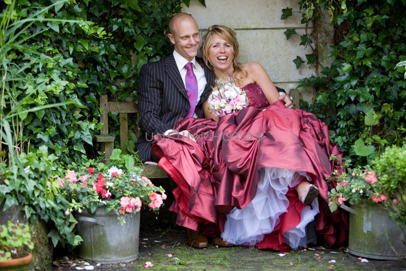Lovely bride and groom sitting in a romantic setting clearly having fun