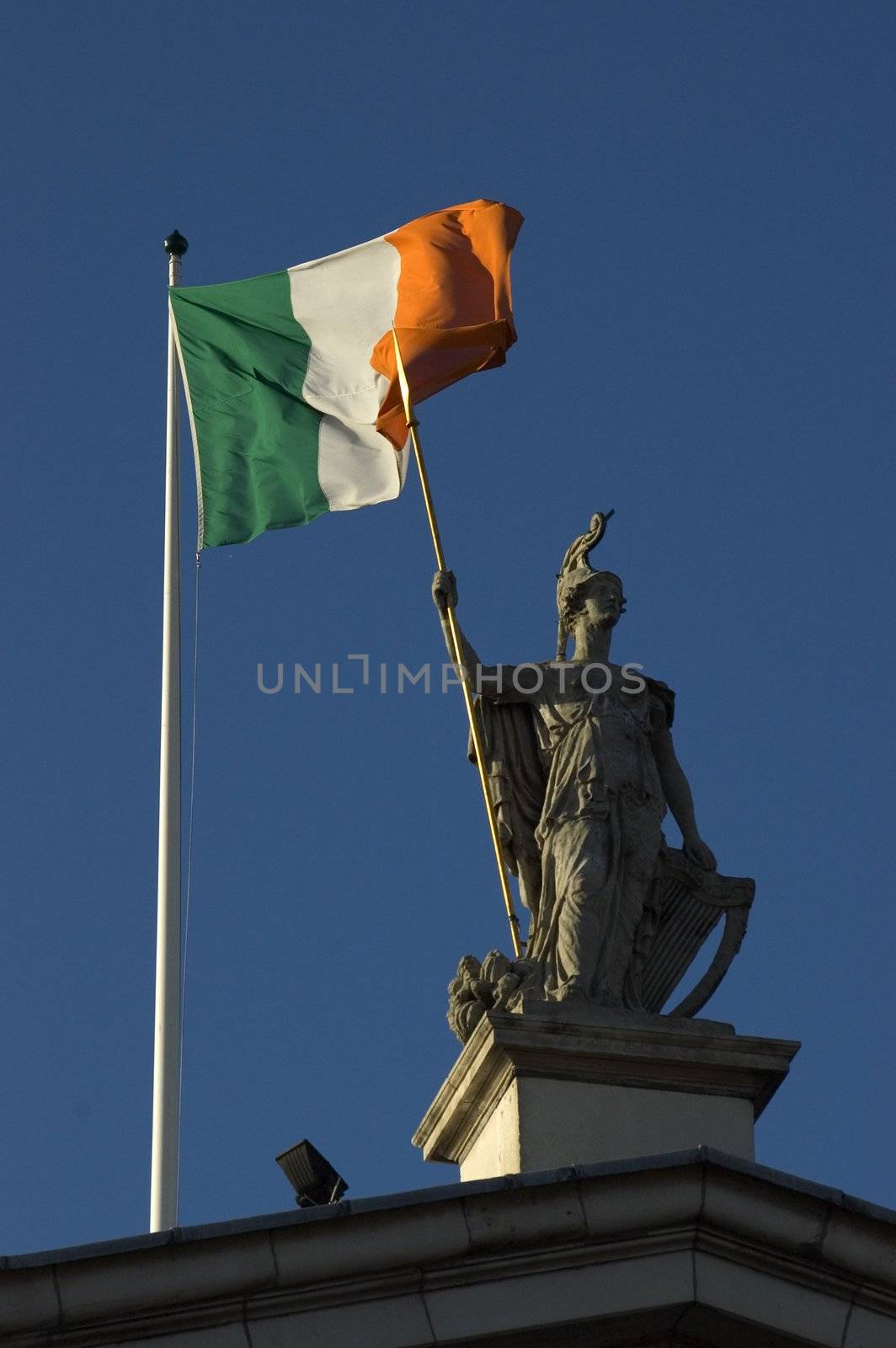 Statue and Irish Flag on top of the GPO in Dublin City shot from below with plenty of bright blue sky