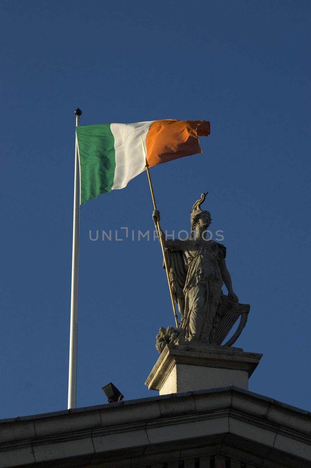 Statue and Irish Flag on top of the GPO in Dublin City shot from below with plenty of bright blue sky