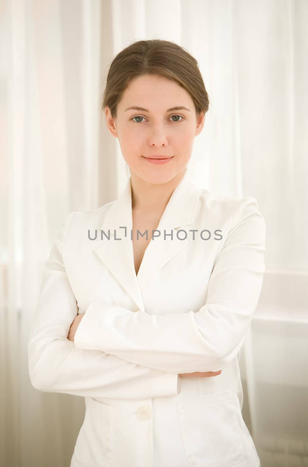 The business woman in a white jacket with dark hair near a window

