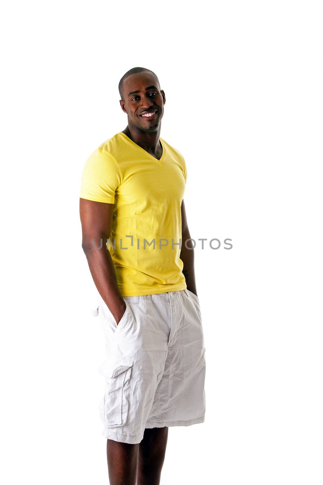 Handsome sporty African American man in yellow shirt and white shorts standing with hands in pocket and big smile, isolated