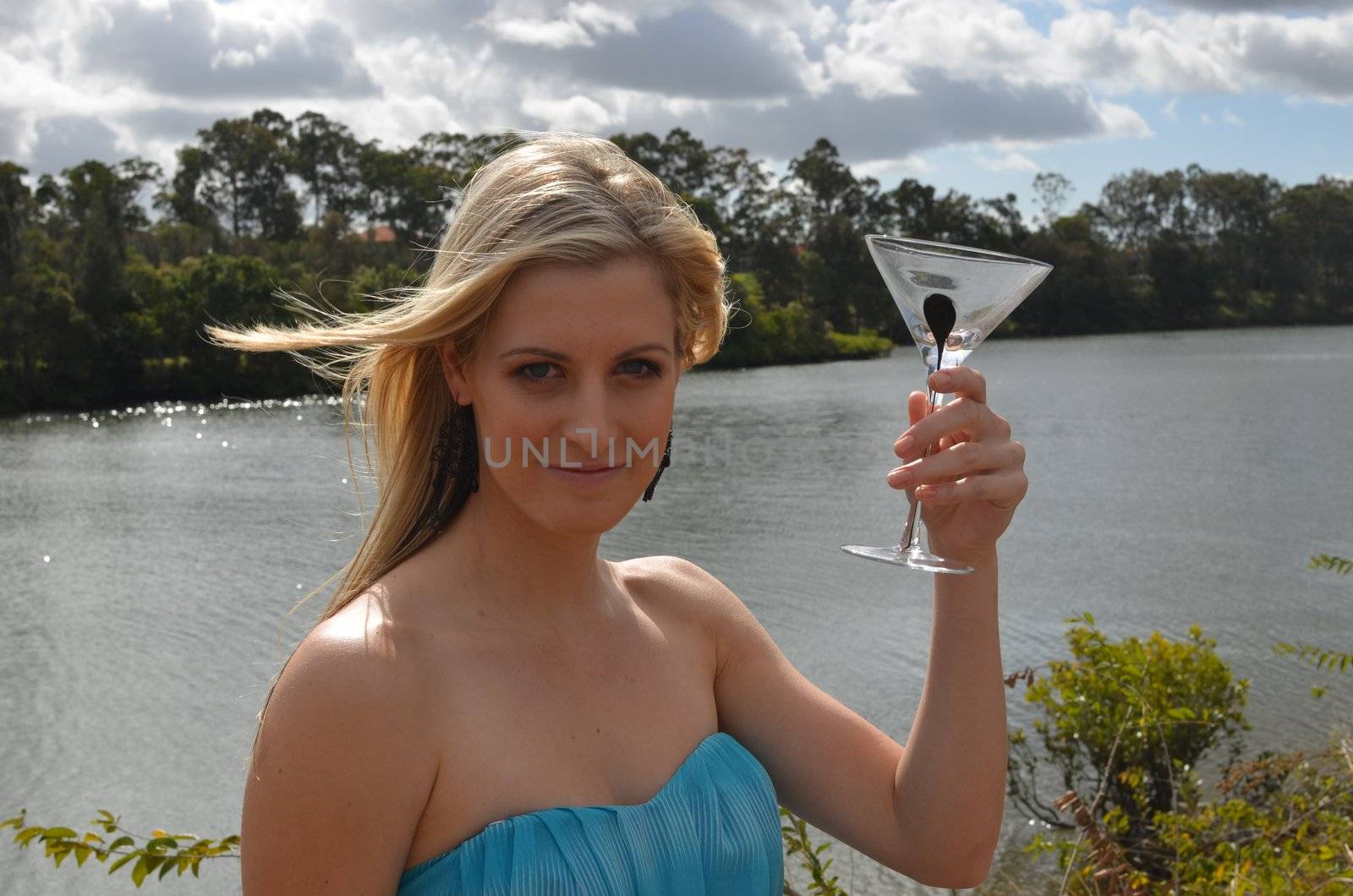 Happy, smiling attractive lady in her cocktail dress with a cocktail glass in her hand