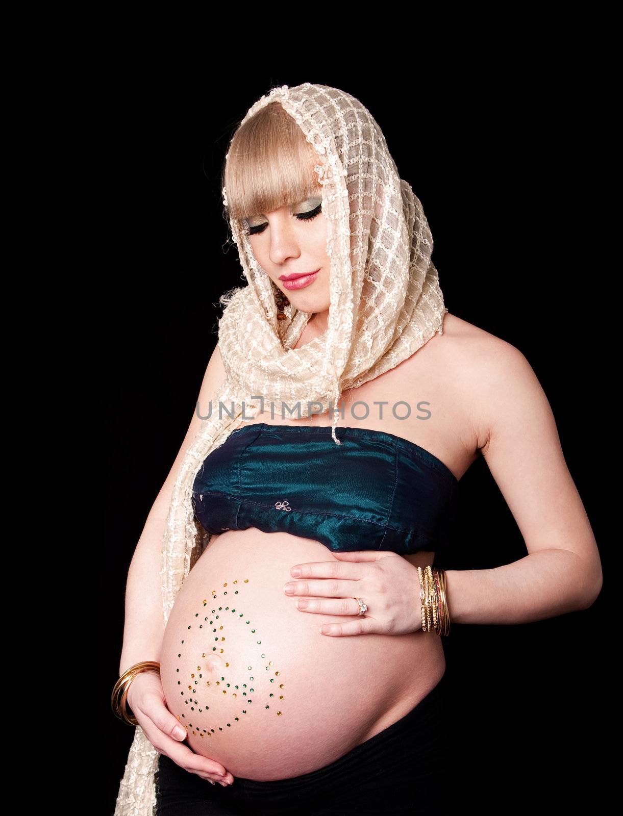 Beautiful pregnant Caucasian woman with head scarf holding naked belly covered with rhinestones, isolated