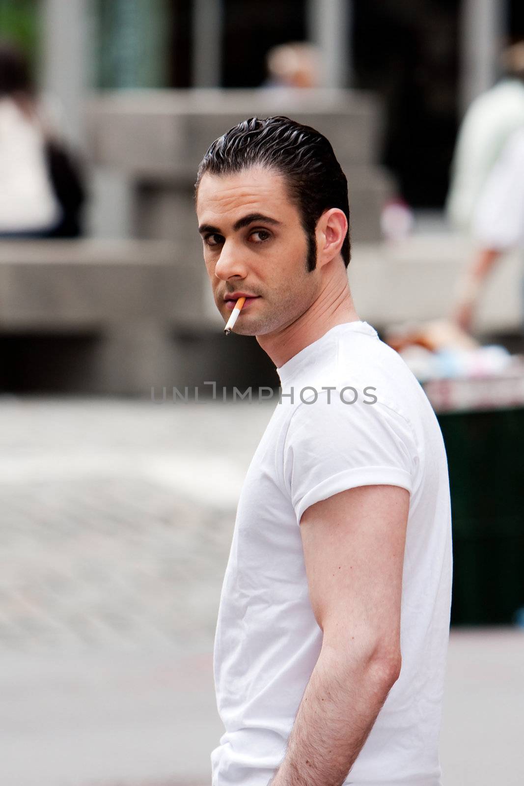Secret surveillance photo of a Caucasian mafia man with cigarette dressed in white t-shirt on the street