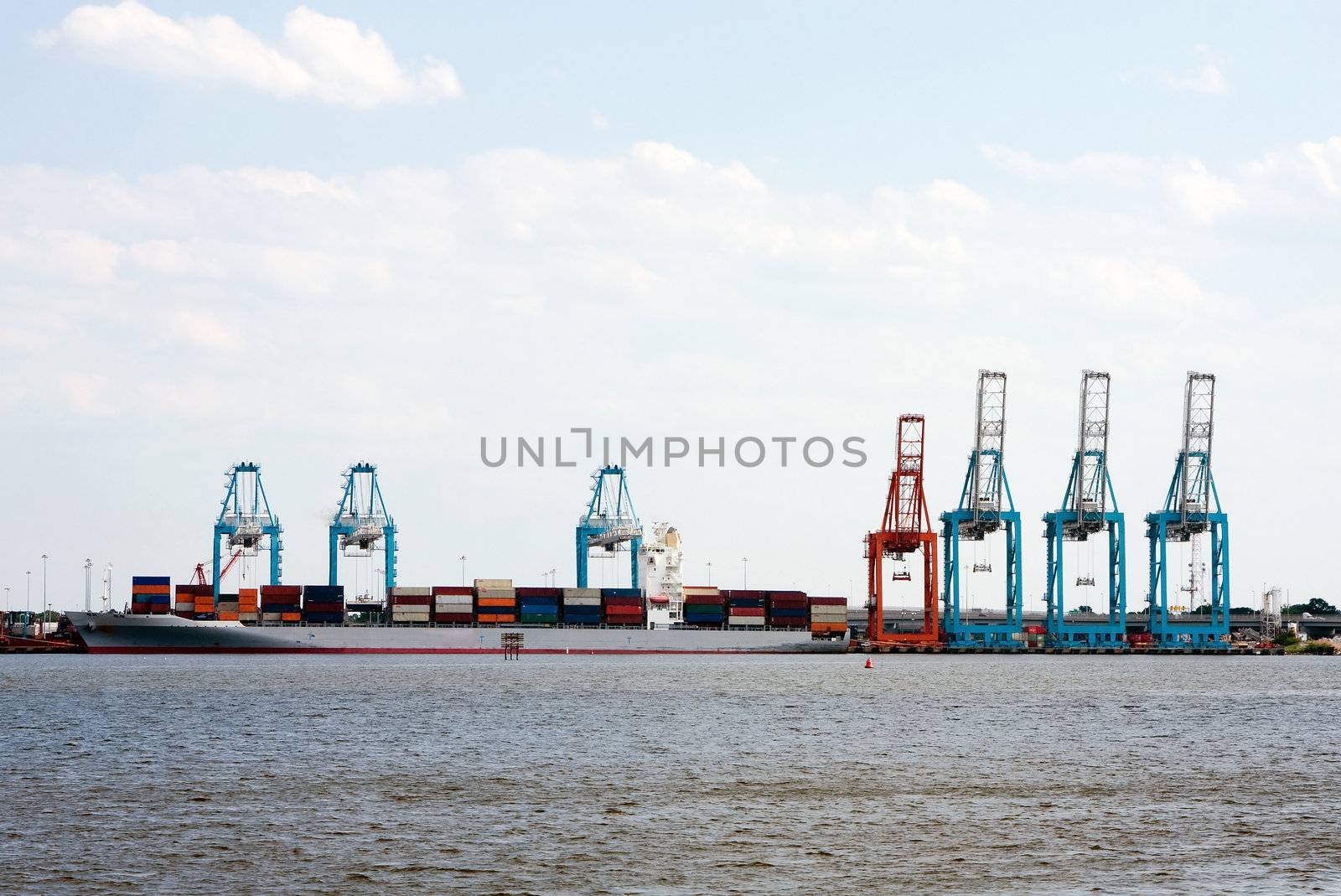 Commercial loading docks where cranes are loading containers filled with merchandise cargo on a transport ship