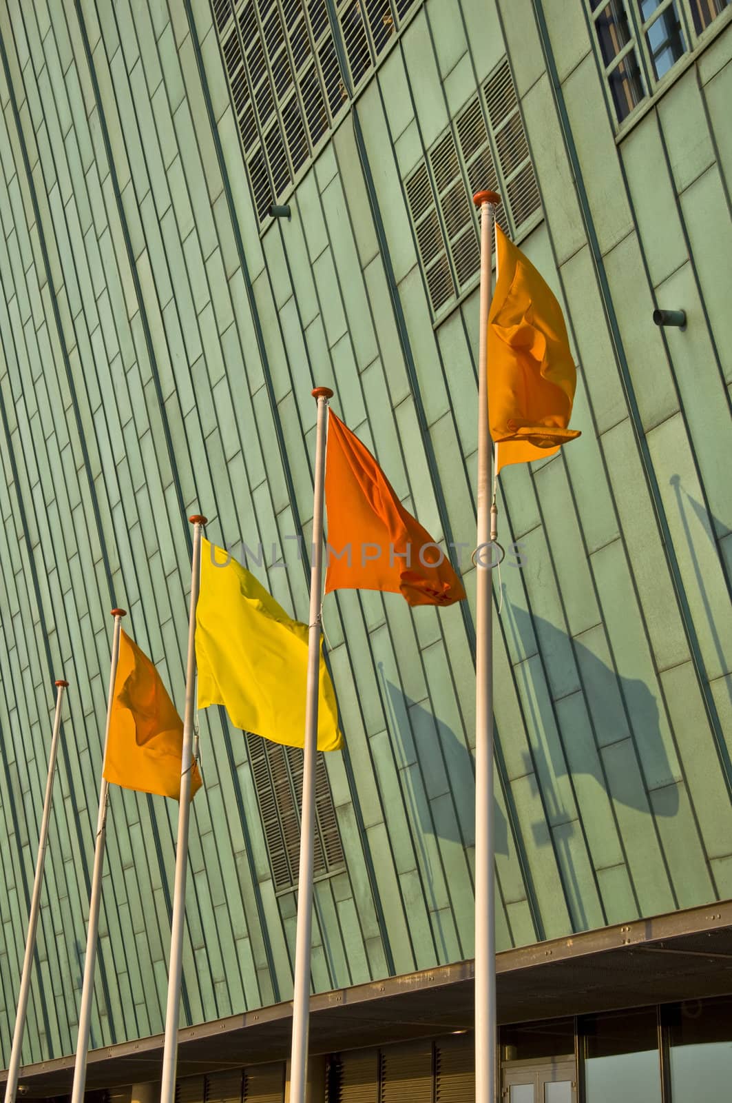 Colored flags in the background of a copper facade. Blowing in the wind. Urban space.