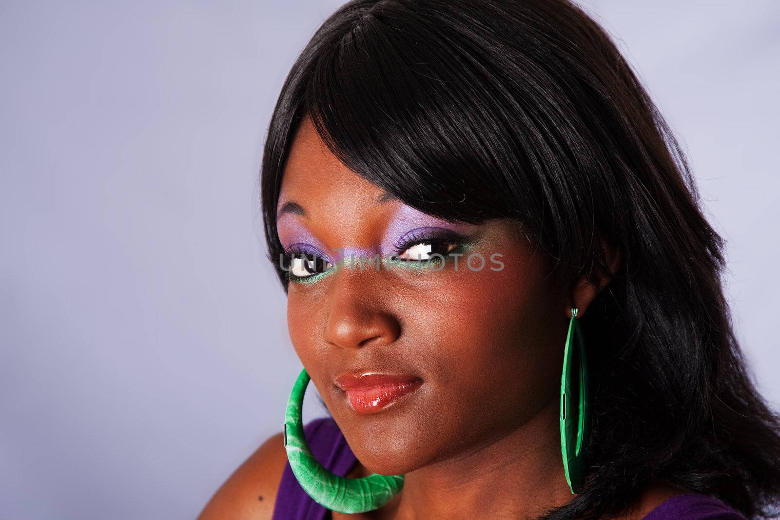 Face portrait of a young beautiful African-American woman with purple-green makeup with long straight black hair, isolated