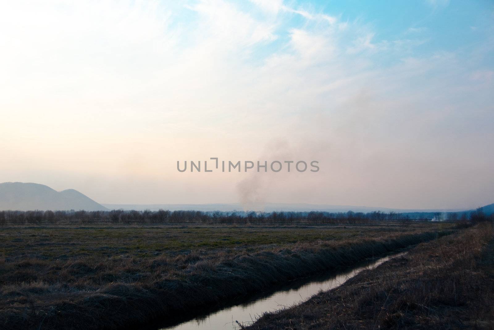 Autumn landscape with a fire smoke in the distance