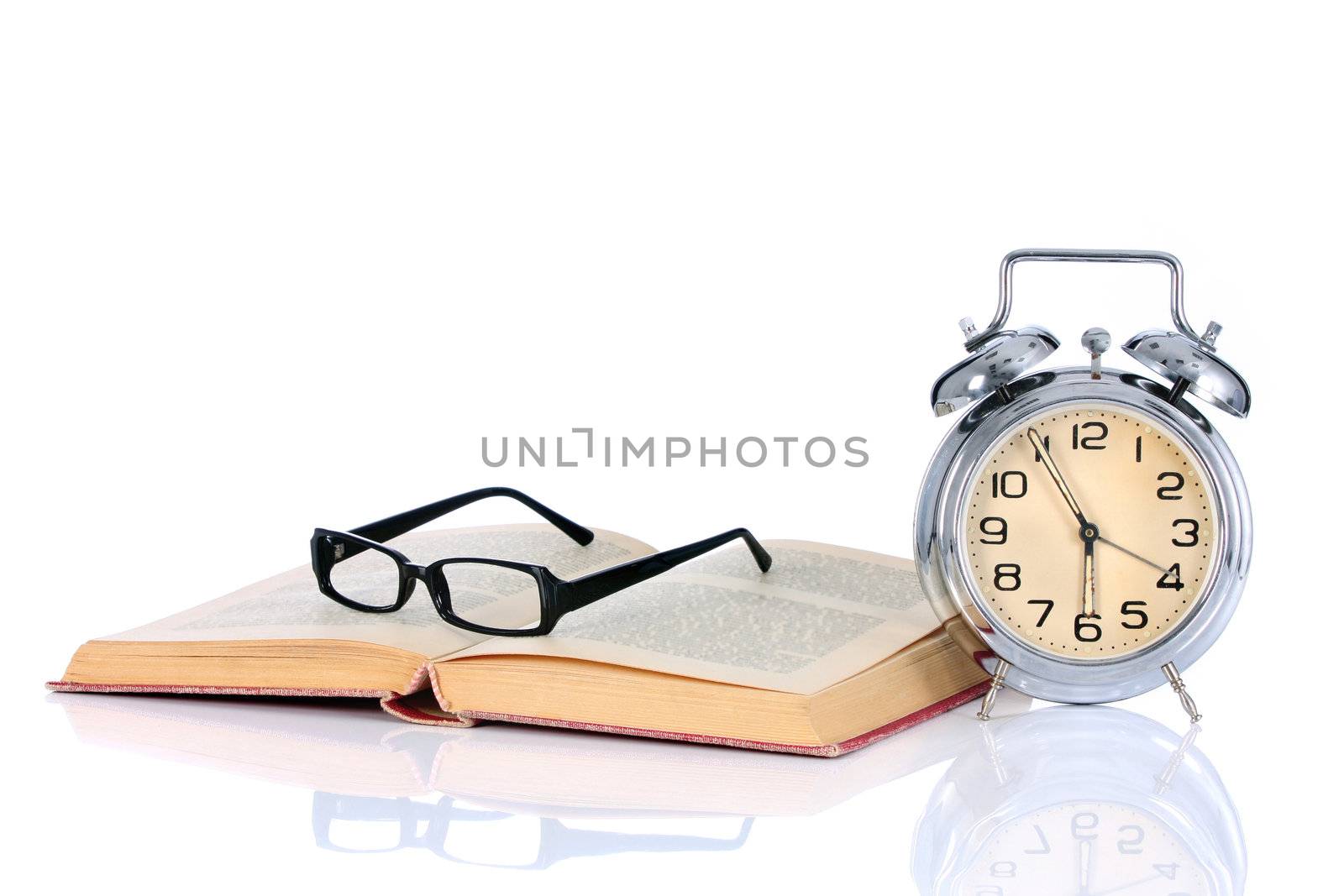 book with alarm clock and eyeglasses on white background
