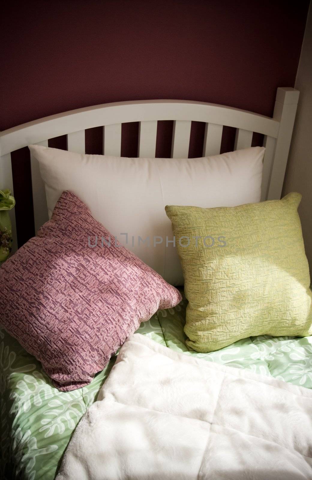 single white bed with colorful pillows by the window