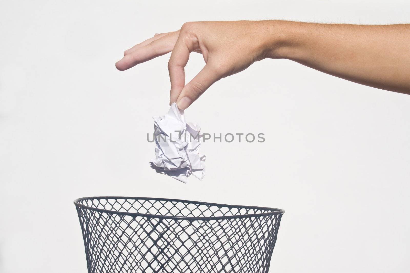 Detail of hand dropping crumpled paper in wire basket