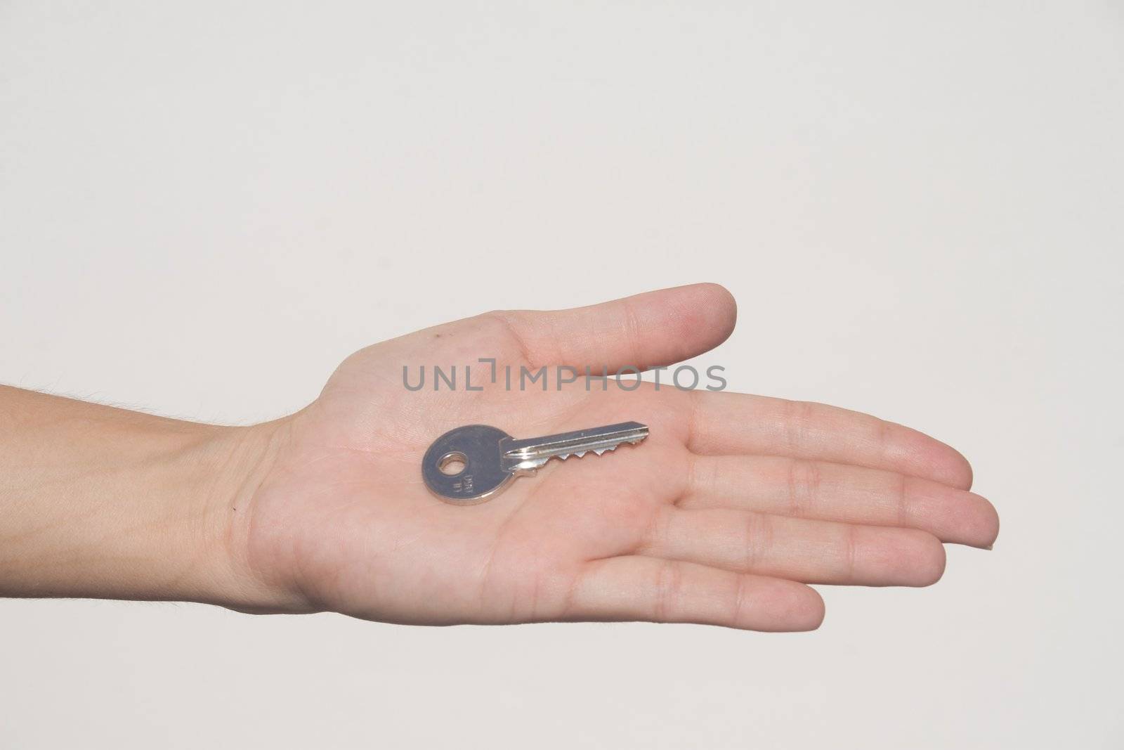 Extended hand with house key in palm against white background