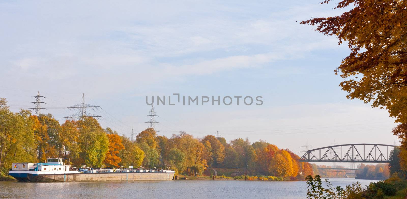 German freight ship anchoring on canal in fall-colored landscape