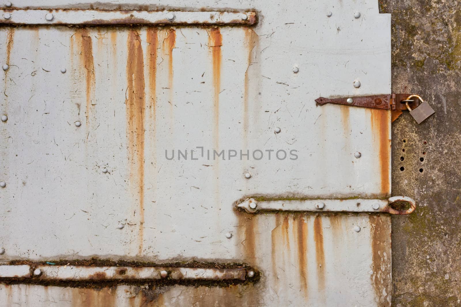 Grungy old steel hatch door secured by padlock