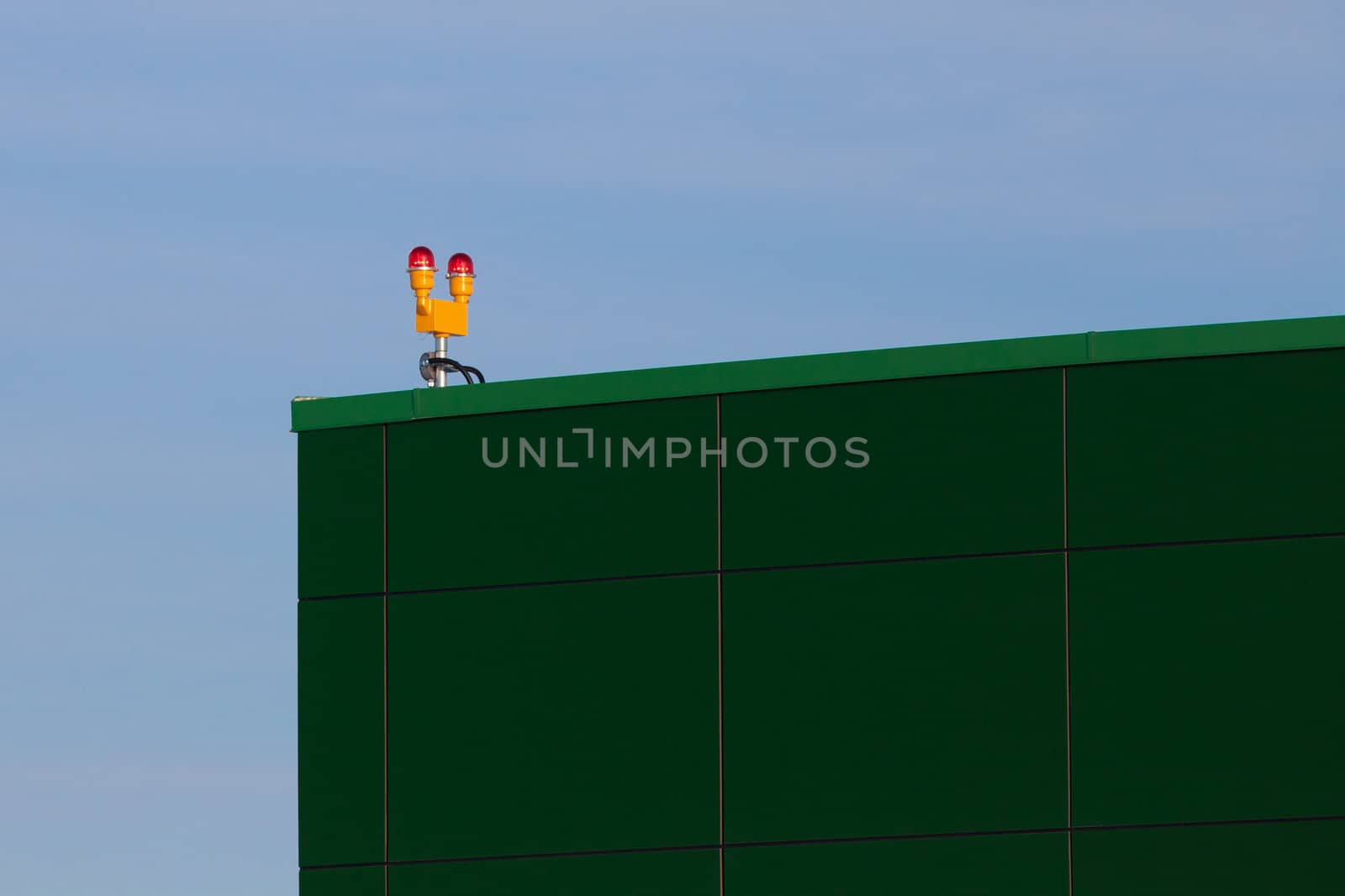 Alarm system lights on corner of huge green commercial building.