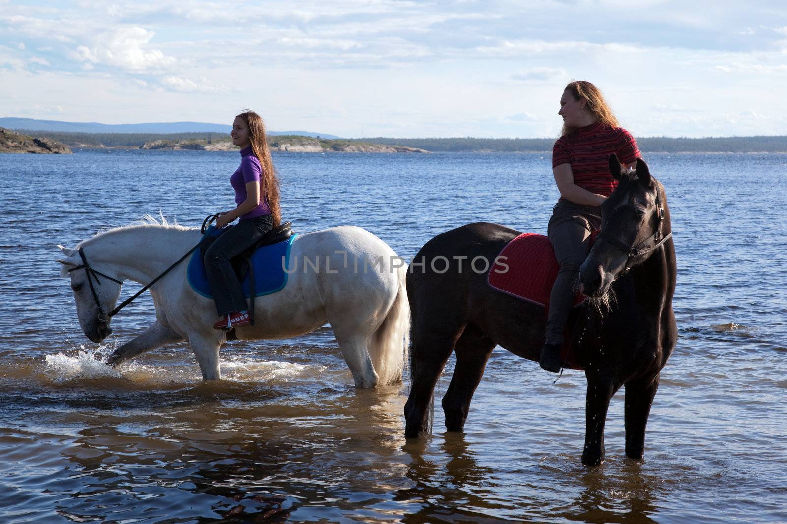 The girls led the horses to water. Summer landscape.