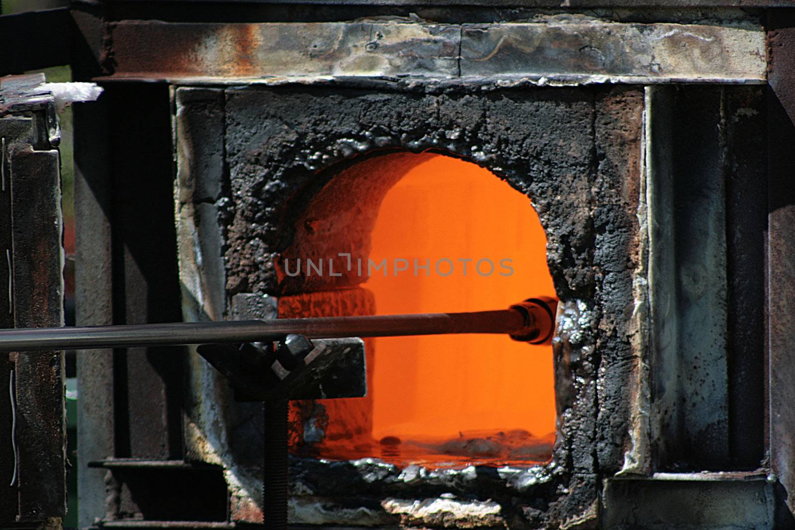 Glass-blower gets preparation from the furnace.