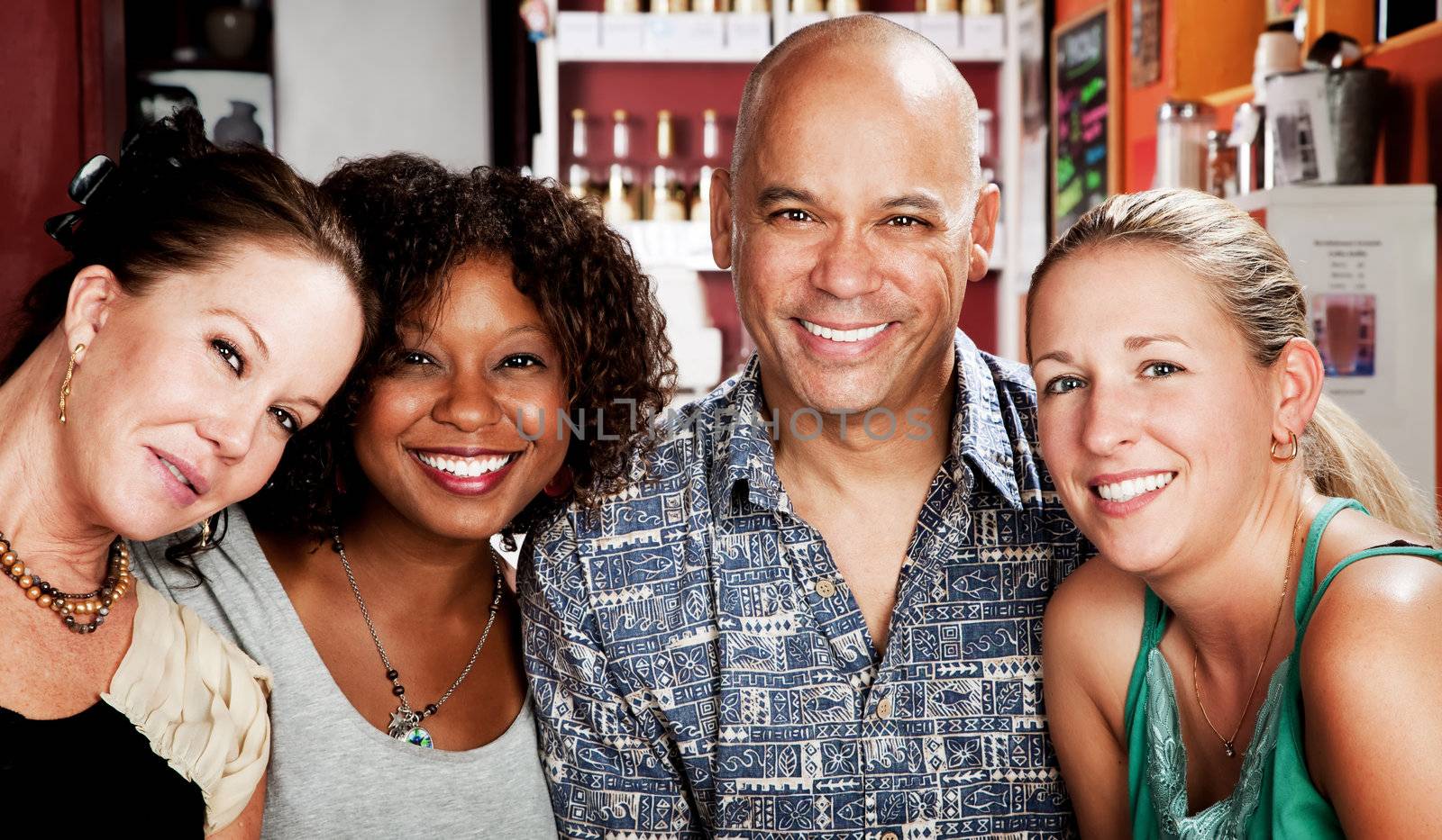 Man with shaved head and three pretty women in coffee house