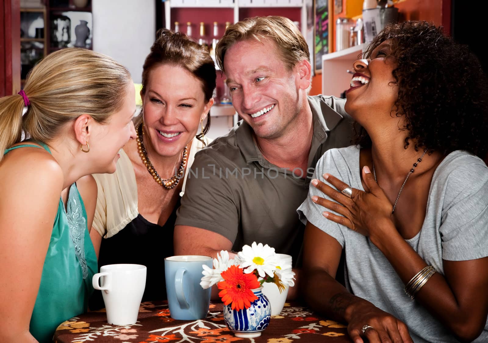 Four friends laughing in a coffee house