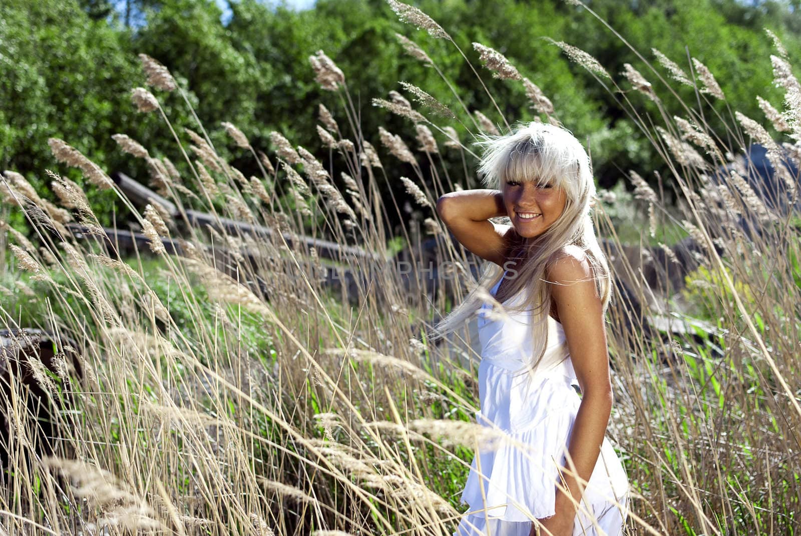 girl in white dress are standing in dry grass at summer daylight