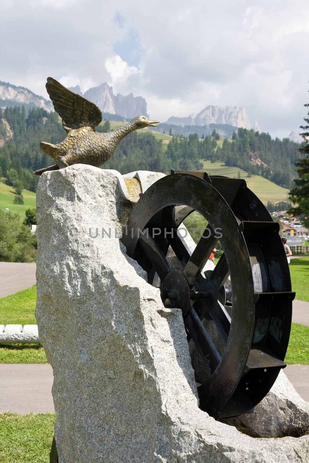 fountain with water moved  wheel and duck sculpture in Soraga, val di Fassa, Italy. On background dolomites mountains