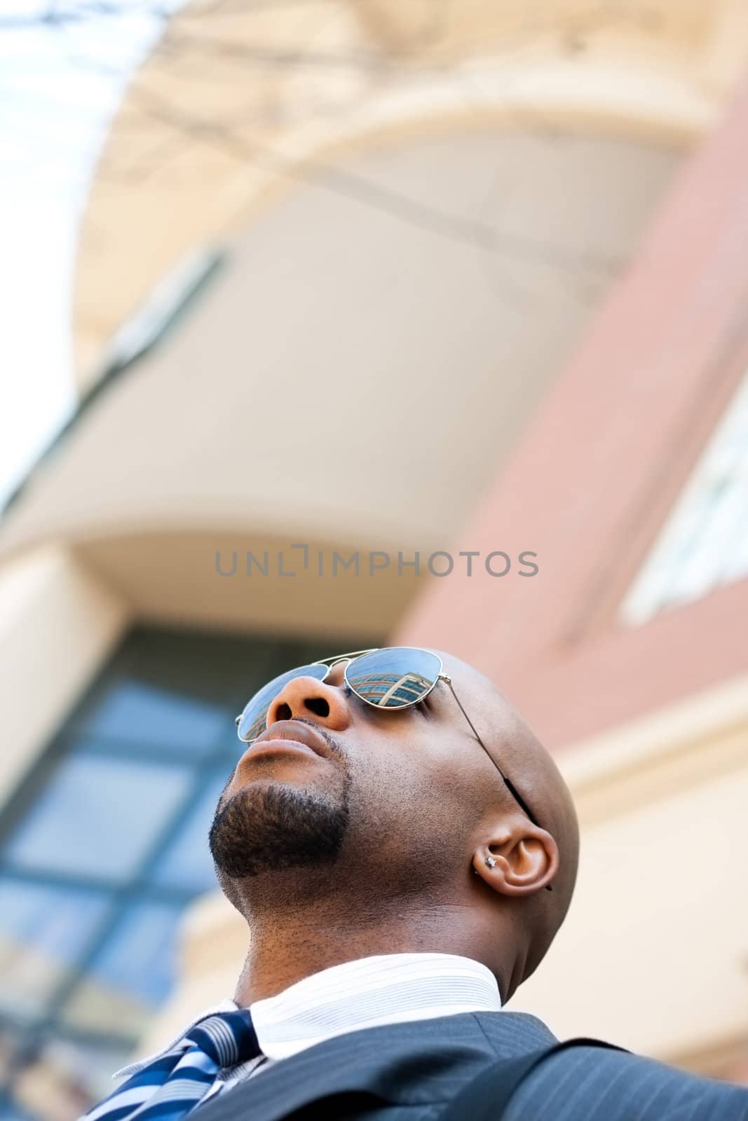An African American business man wearing his sunglasses and business suit in the city with copy space.