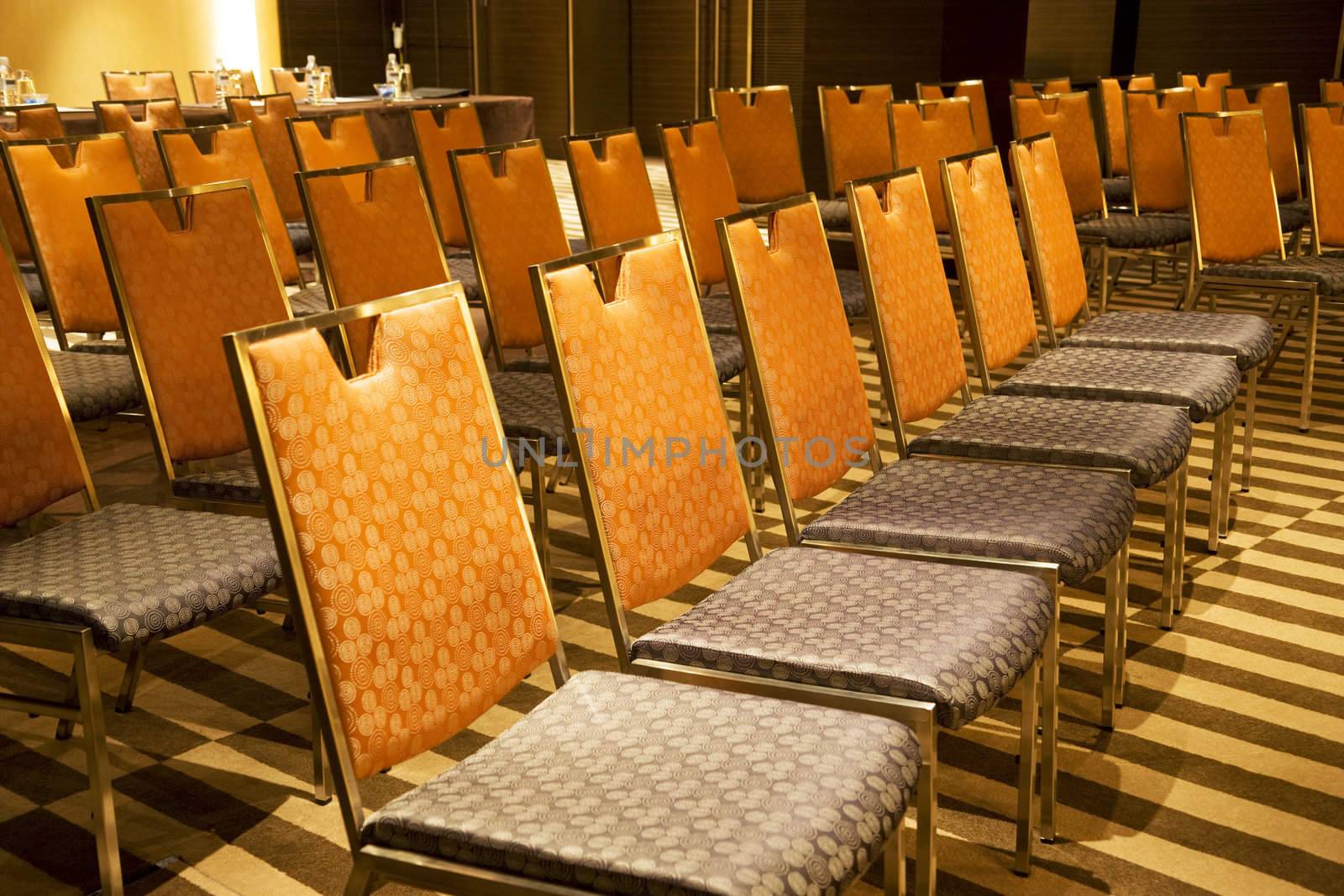 Image of rows of colourful chairs at a seminar room.
