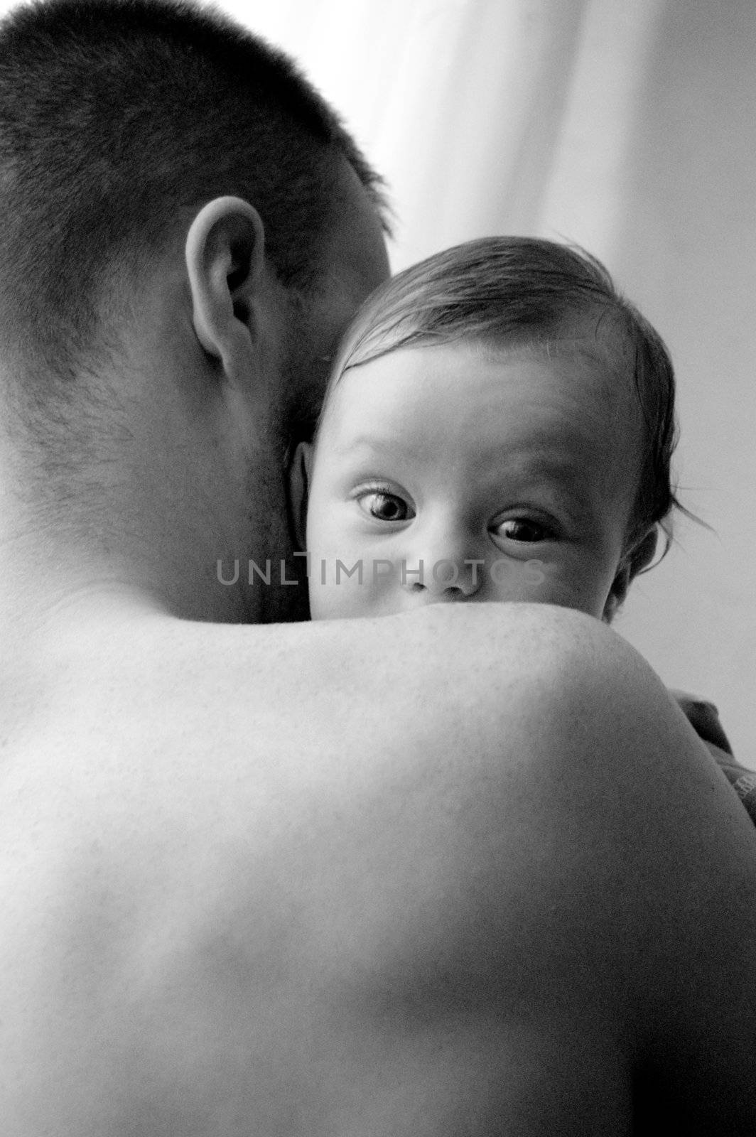 Portrait of baby boy looking through his fathet shoulder