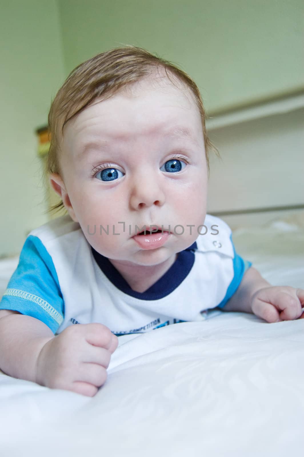 Blue-eyed baby boy lying on bed