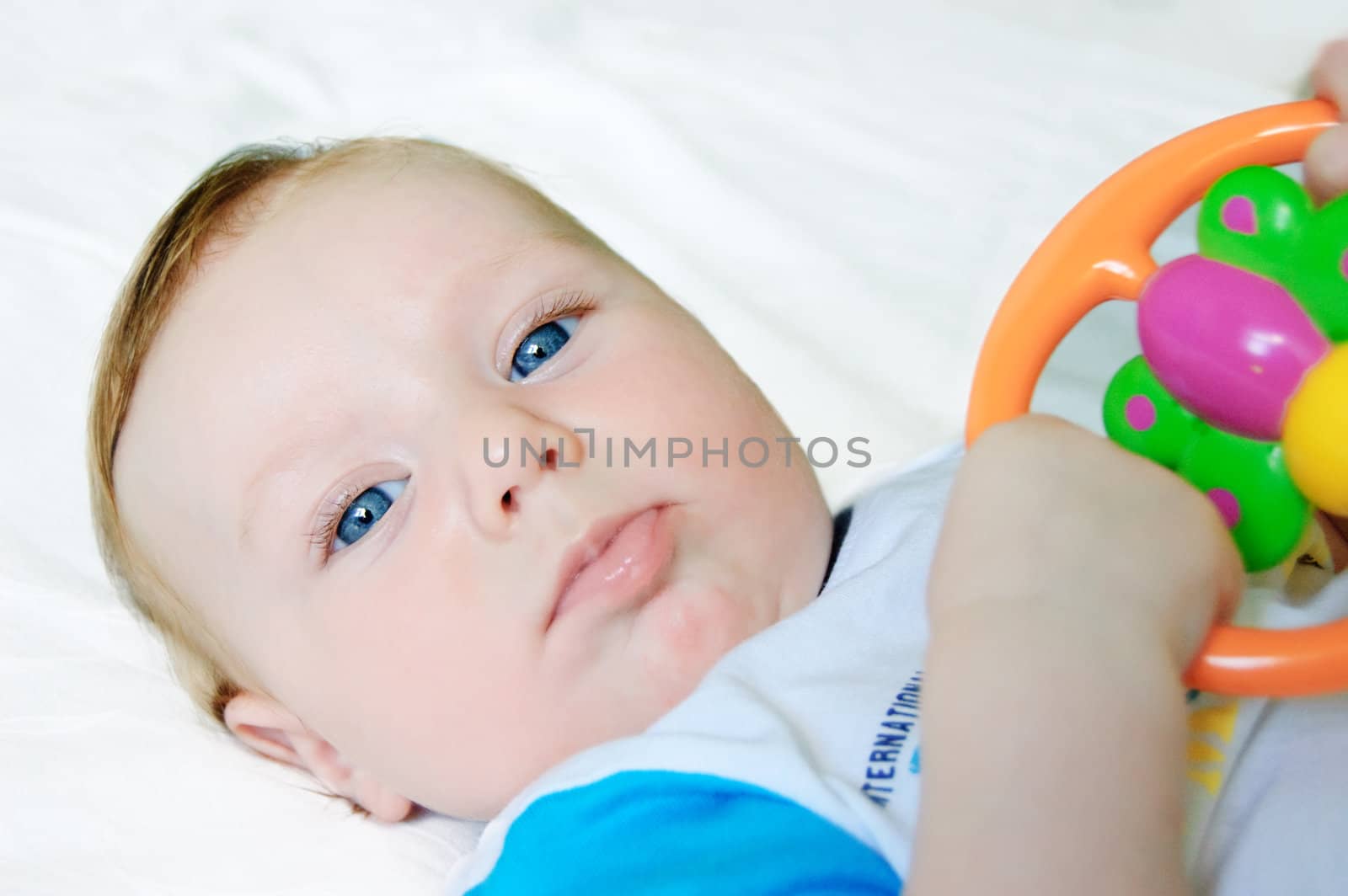 Little baby boy holding rattle over light background