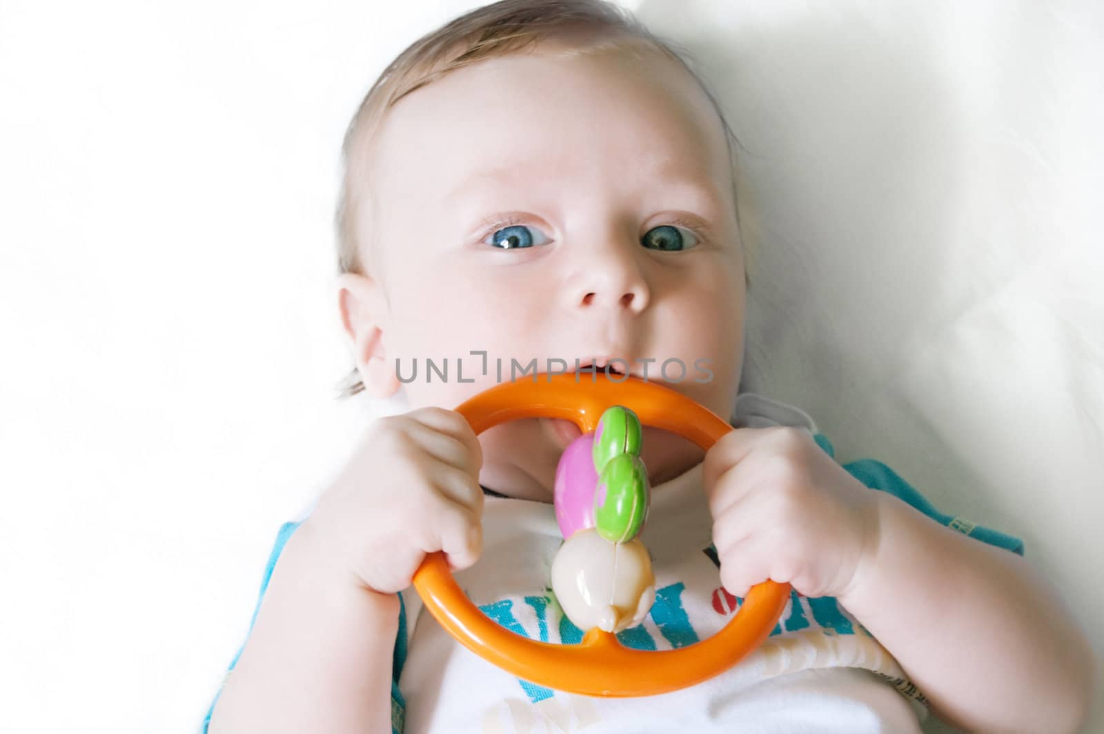 Little baby boy playing with rattle over light background