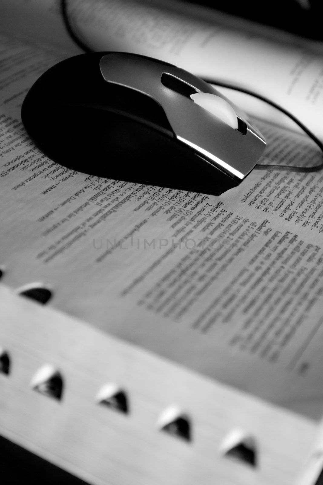 black and white image of a computer mouse on a dictionary. conceptual image of web browsing or e-learning or e-books